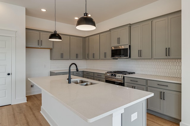 kitchen with appliances with stainless steel finishes, a center island with sink, gray cabinetry, and sink