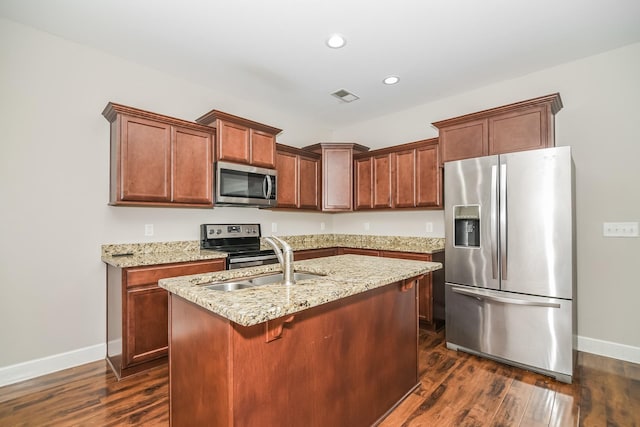 kitchen featuring light stone countertops, sink, stainless steel appliances, dark hardwood / wood-style flooring, and a center island with sink