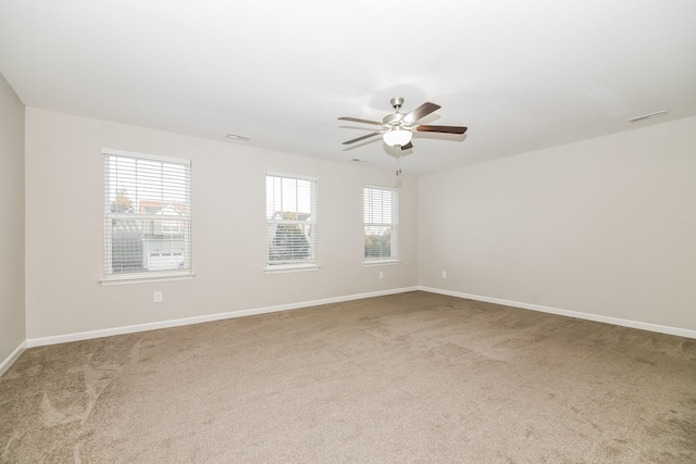 spare room featuring carpet floors, a wealth of natural light, and ceiling fan