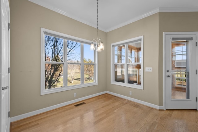 unfurnished dining area featuring wood-type flooring, ornamental molding, and an inviting chandelier