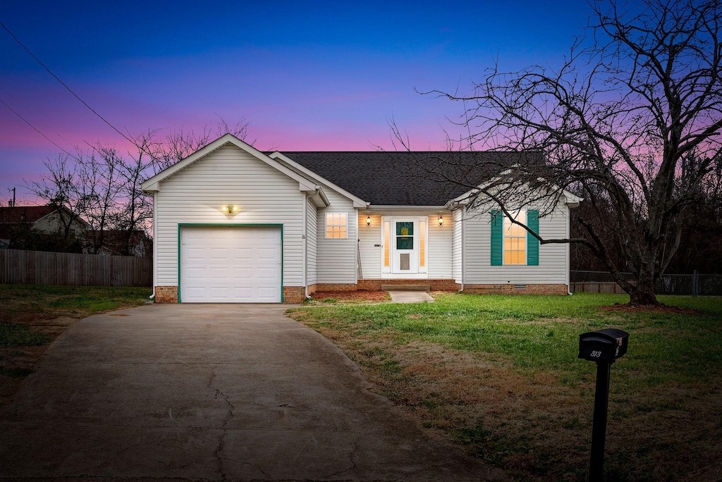 single story home featuring a lawn and a garage