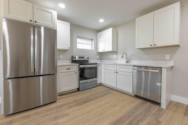 kitchen featuring appliances with stainless steel finishes, light hardwood / wood-style floors, white cabinetry, and sink