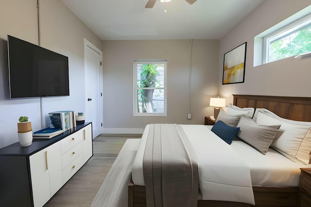 bedroom with multiple windows, light hardwood / wood-style floors, and ceiling fan