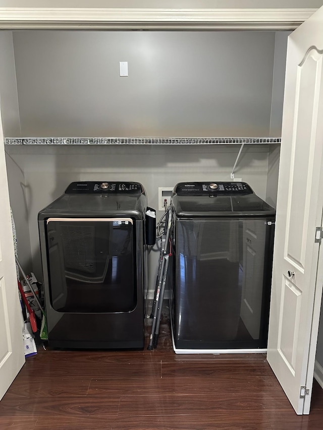 clothes washing area with washing machine and clothes dryer and dark wood-type flooring