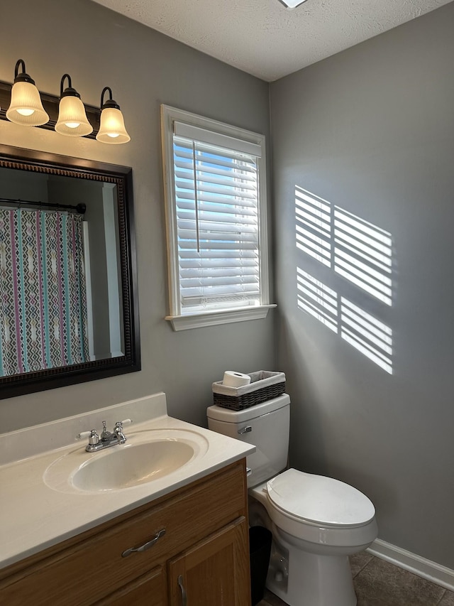 bathroom with tile patterned flooring, vanity, toilet, and a textured ceiling