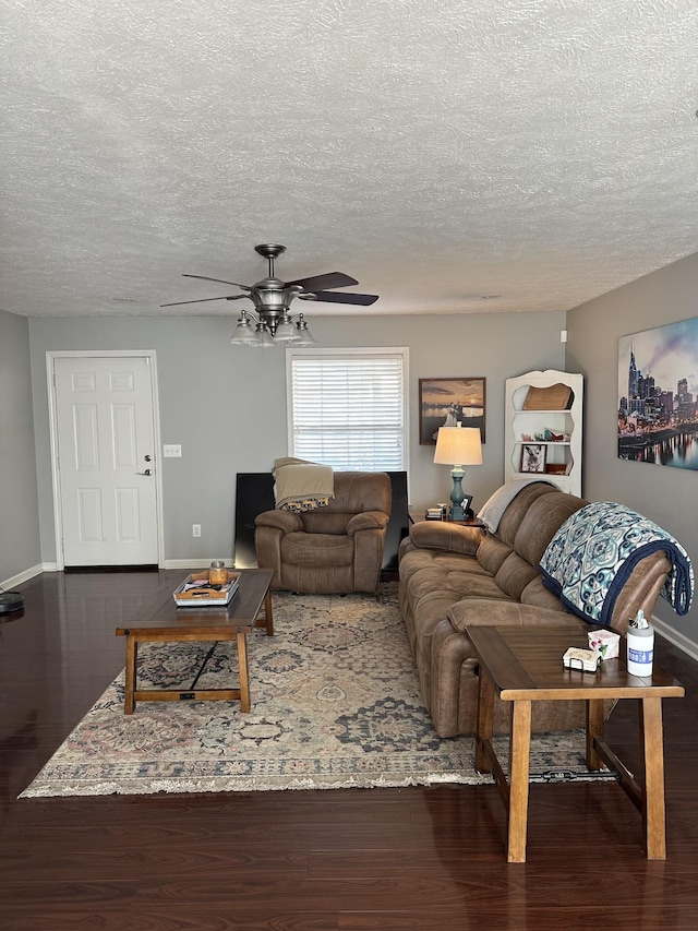 living room featuring ceiling fan, dark hardwood / wood-style flooring, and a textured ceiling