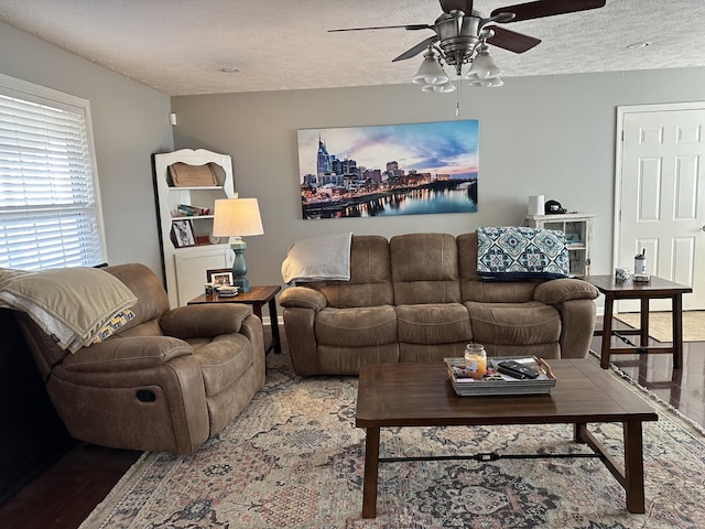 living room with hardwood / wood-style flooring, ceiling fan, and a textured ceiling