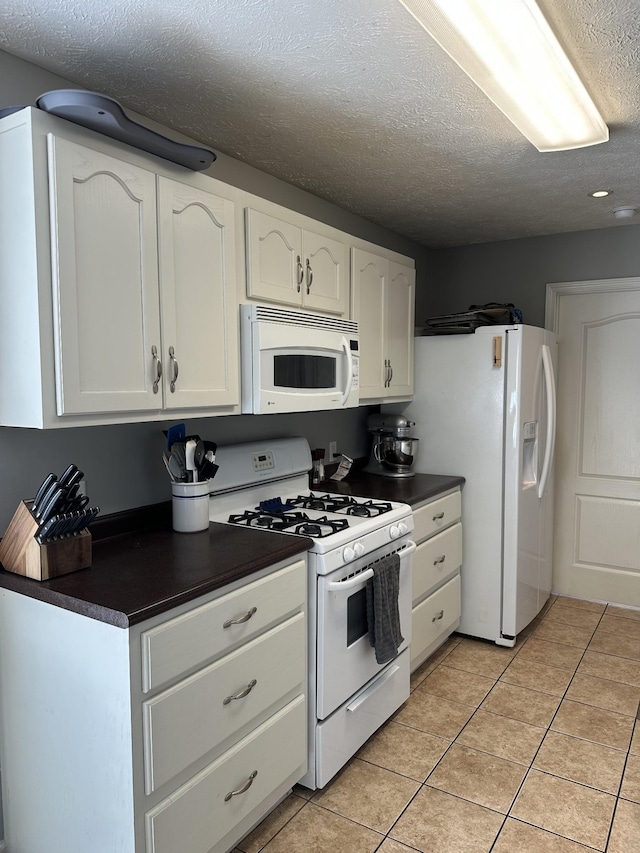 kitchen featuring white cabinets, white appliances, a textured ceiling, and light tile patterned floors