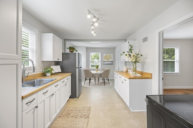 kitchen with white cabinetry, sink, butcher block countertops, range with electric stovetop, and light tile patterned flooring