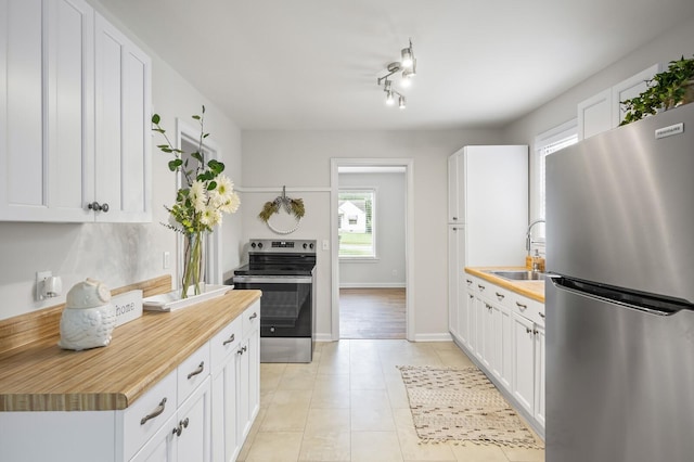 kitchen with butcher block counters, sink, white cabinetry, and stainless steel appliances