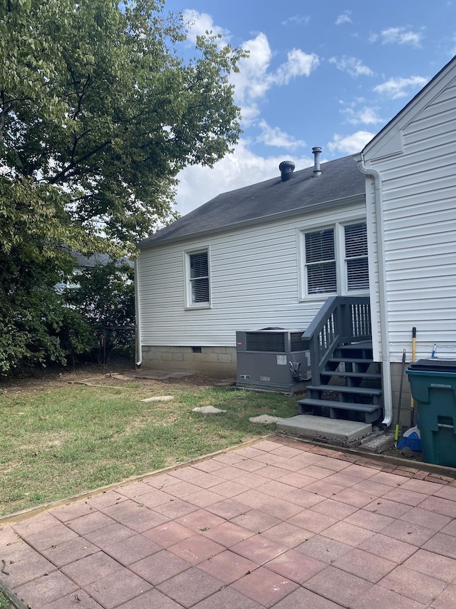 exterior space featuring a lawn, cooling unit, and a patio area