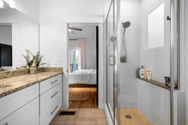 bathroom with wood-type flooring, vanity, a shower with door, and ceiling fan