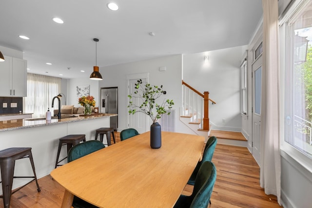 dining room featuring light wood-type flooring, a healthy amount of sunlight, and sink