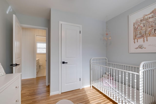 bedroom featuring a crib and light hardwood / wood-style flooring