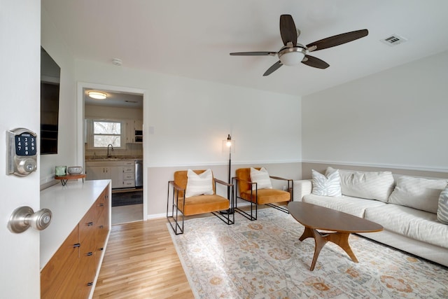 living room with ceiling fan, sink, and light hardwood / wood-style floors