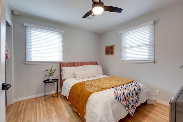 bedroom with ceiling fan, multiple windows, and light hardwood / wood-style flooring