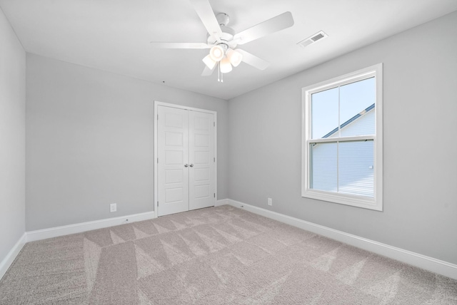 unfurnished bedroom with ceiling fan, a closet, and light colored carpet