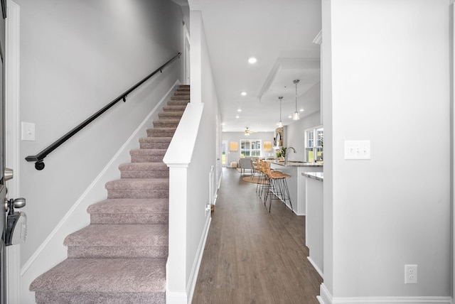 staircase featuring hardwood / wood-style floors, ceiling fan, and sink