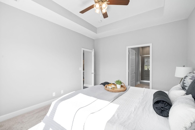 carpeted bedroom with ceiling fan, a raised ceiling, and connected bathroom