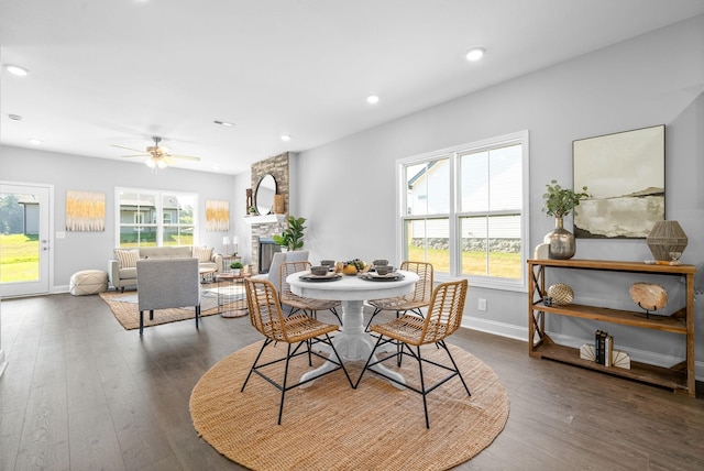 dining space featuring ceiling fan, a fireplace, and dark hardwood / wood-style floors