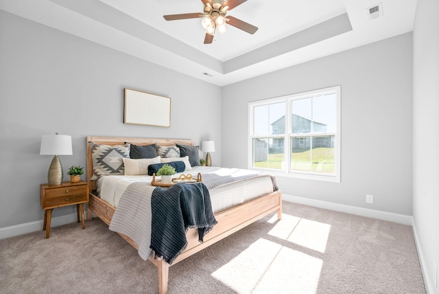 bedroom featuring a tray ceiling, ceiling fan, and light colored carpet