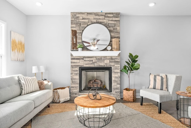 living room featuring a stone fireplace and ceiling fan