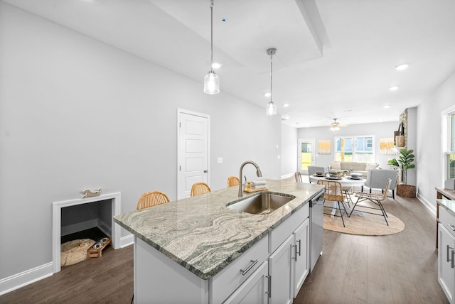 kitchen featuring ceiling fan, dishwasher, sink, light stone countertops, and a kitchen island with sink