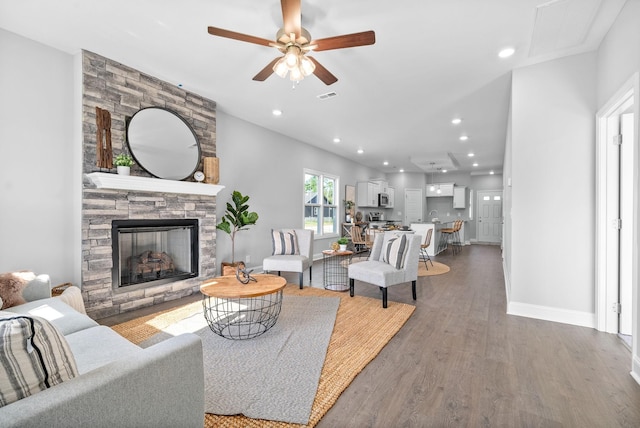 living room featuring hardwood / wood-style floors, ceiling fan, and a fireplace