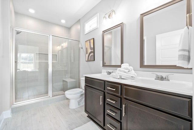 bathroom featuring vanity, toilet, a shower with shower door, and wood-type flooring