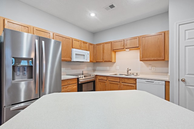 kitchen featuring a textured ceiling, light brown cabinets, sink, and appliances with stainless steel finishes