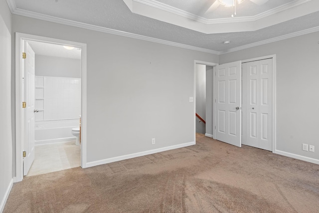 unfurnished bedroom featuring ensuite bathroom, ornamental molding, light colored carpet, ceiling fan, and a closet