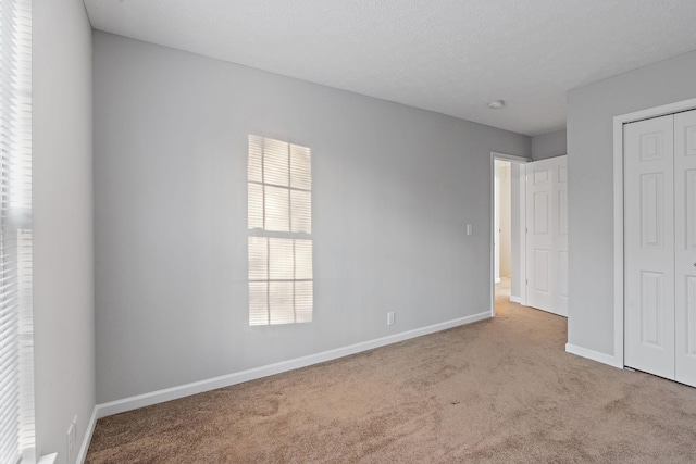 unfurnished bedroom with light colored carpet, a textured ceiling, and a closet