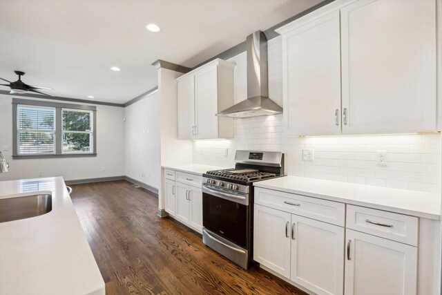 kitchen featuring wall chimney exhaust hood, dark hardwood / wood-style floors, ceiling fan, gas stove, and white cabinetry