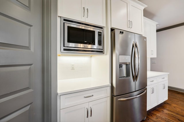 kitchen with white cabinets, decorative backsplash, ornamental molding, and stainless steel appliances