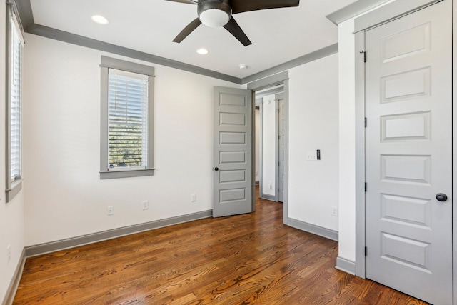 unfurnished bedroom with ceiling fan and dark wood-type flooring