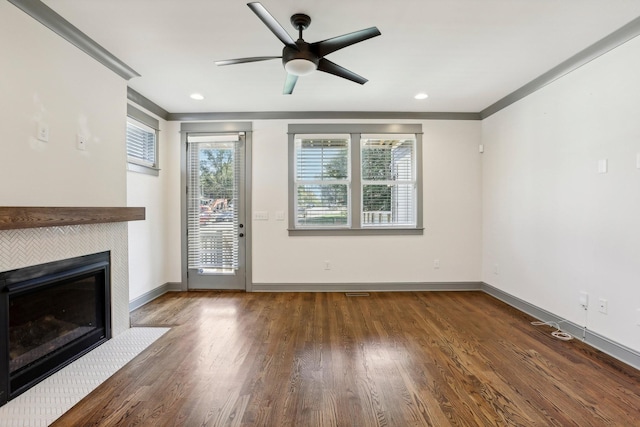 unfurnished living room featuring a tile fireplace, ceiling fan, and dark hardwood / wood-style floors