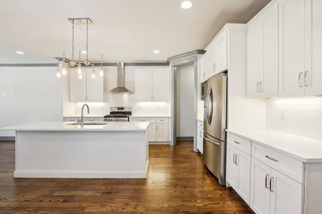 kitchen with appliances with stainless steel finishes, sink, wall chimney range hood, decorative light fixtures, and white cabinets