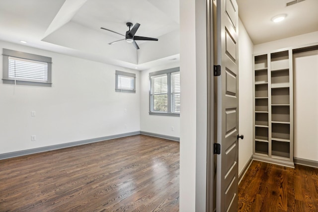 walk in closet with dark hardwood / wood-style floors, ceiling fan, and a tray ceiling