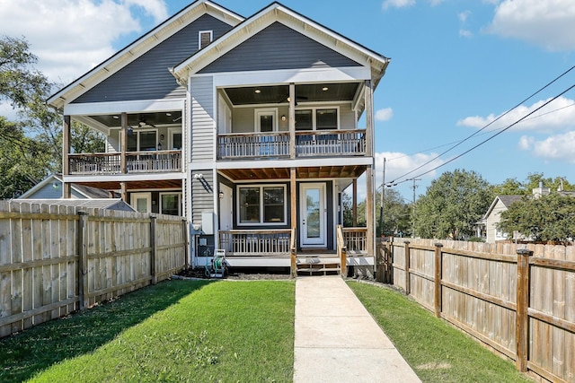 rear view of house featuring a porch, a balcony, and a yard