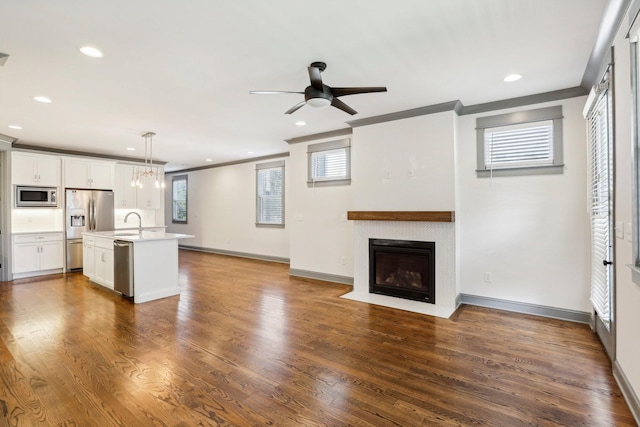 unfurnished living room with dark wood-type flooring, ceiling fan, crown molding, and sink