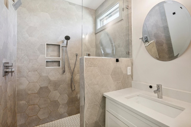 bathroom featuring a tile shower, vanity, and tile walls