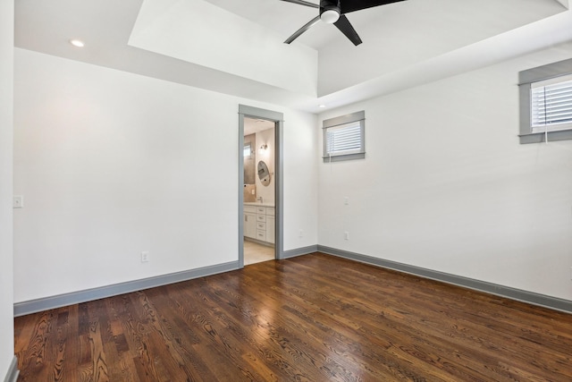 spare room featuring a tray ceiling, ceiling fan, and wood-type flooring