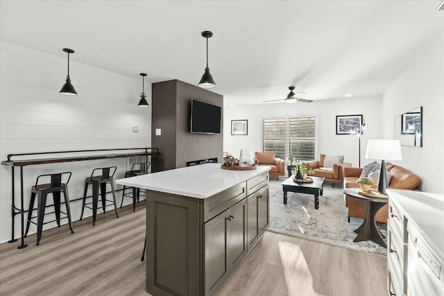 kitchen with a breakfast bar, pendant lighting, and light hardwood / wood-style floors