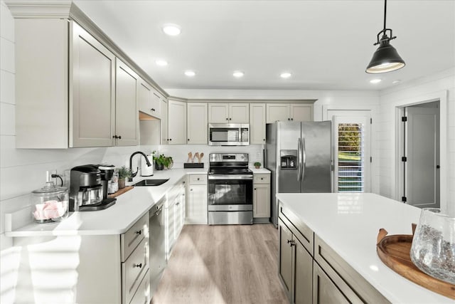 kitchen with gray cabinetry, sink, light wood-type flooring, appliances with stainless steel finishes, and decorative light fixtures