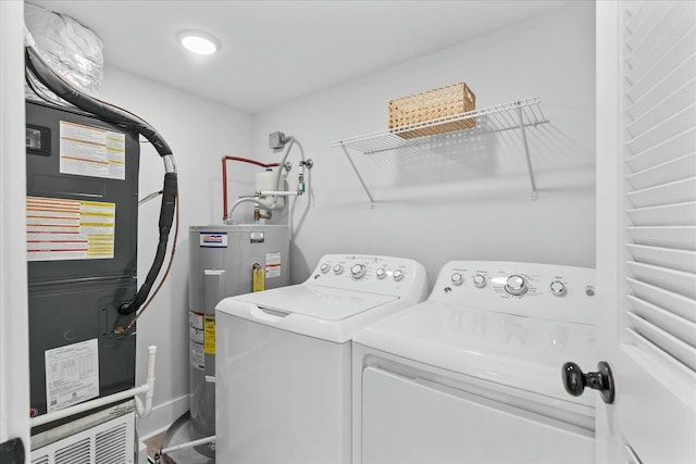 clothes washing area with heating unit, water heater, and independent washer and dryer