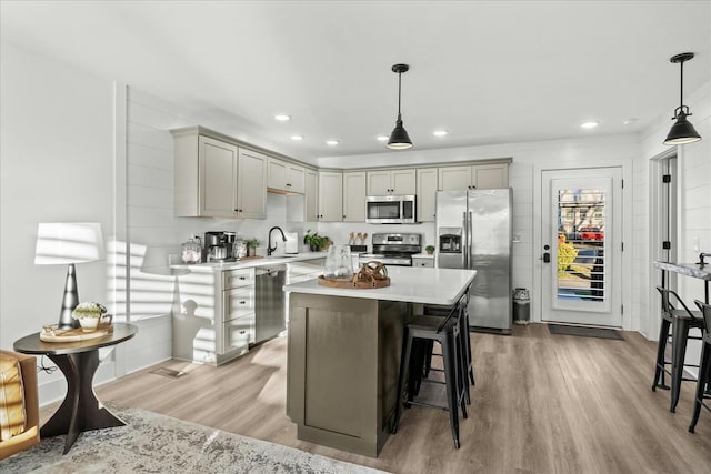 kitchen with appliances with stainless steel finishes, light wood-type flooring, pendant lighting, and gray cabinetry