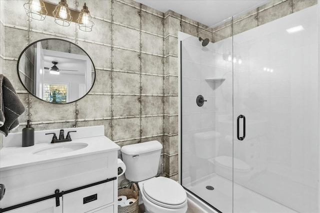 bathroom with ceiling fan, vanity, an enclosed shower, and toilet