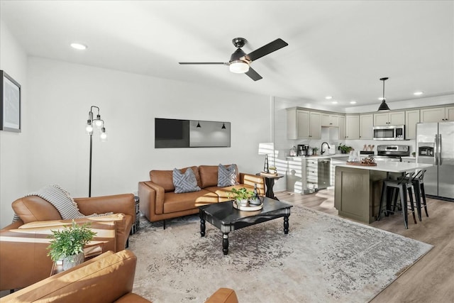 living room with ceiling fan, light hardwood / wood-style flooring, and sink