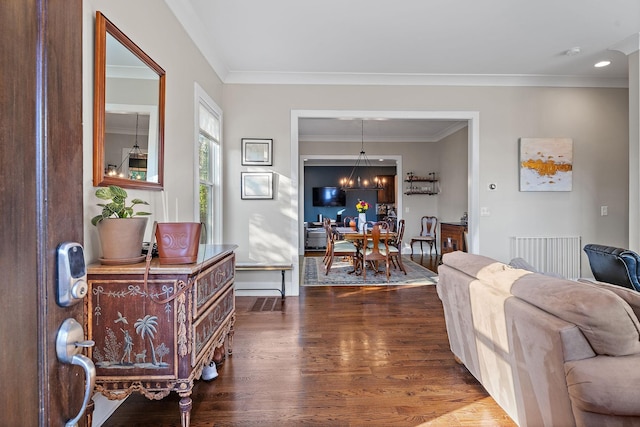 living room with dark hardwood / wood-style flooring, ornamental molding, and a notable chandelier