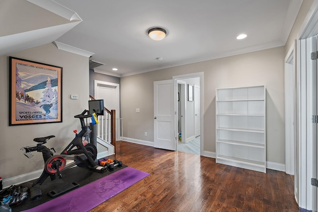 exercise room with crown molding and dark wood-type flooring